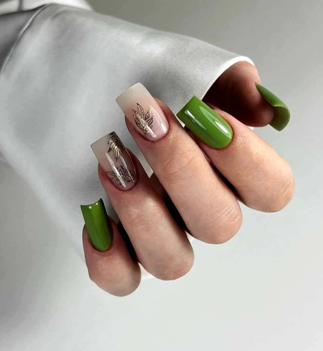 Short green nails with translucent panels and silver accents