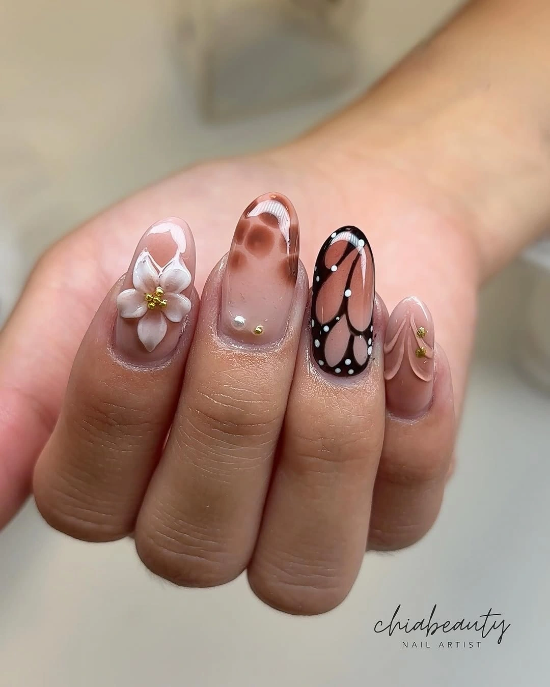 Short neutral nails with a white flower and dark graphic accent