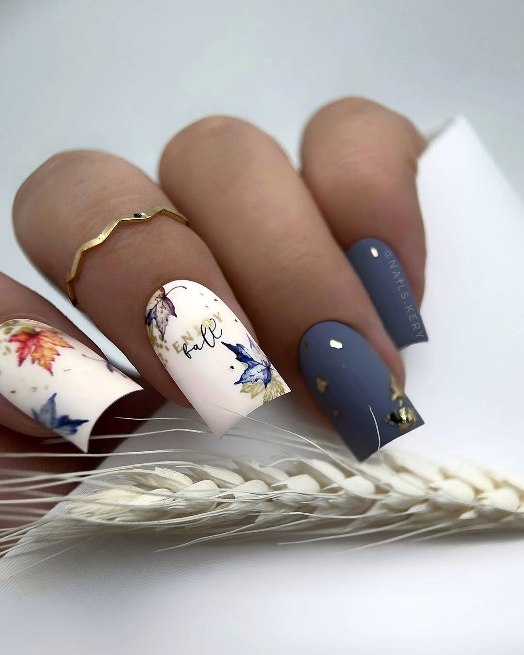 Short navy nails with pale floral accents and tiny gold details