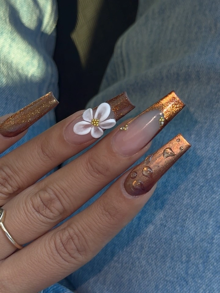 Long translucent square nails with copper glitter tips and flower accent
