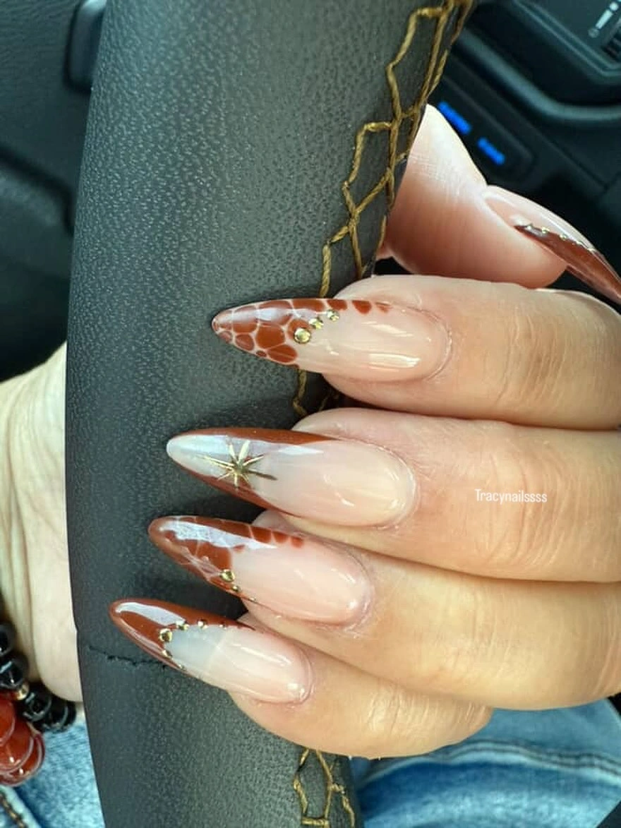 Long pointed nude nails with warm tortoiseshell tips and gold details