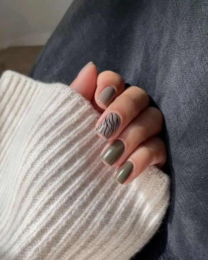 Olive green nails with one white accent and black wavy lines
