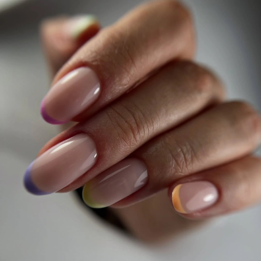 Sheer nude almond nails with slim purple yellow and green tips