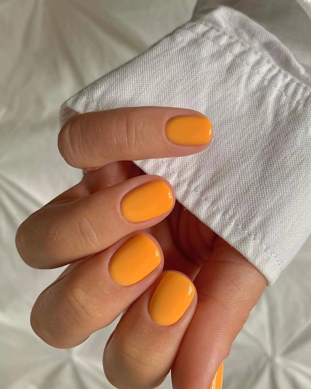 Short rounded matte pumpkin orange nails in a single solid color