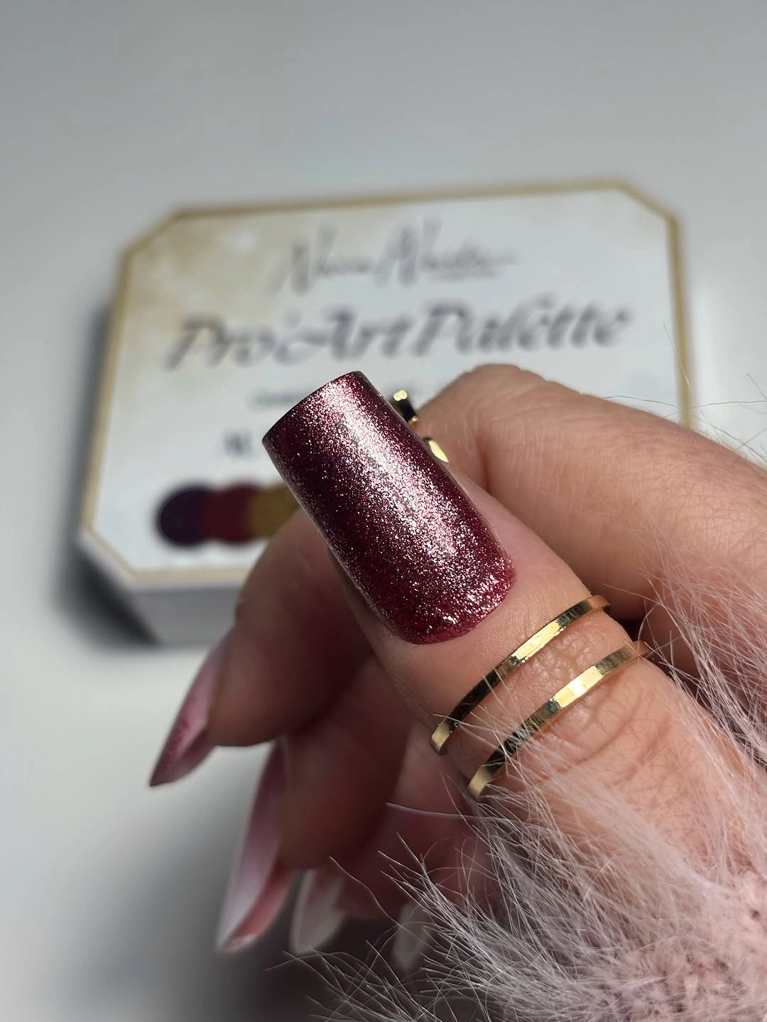 Long tapered burgundy nails covered in deep fine glitter