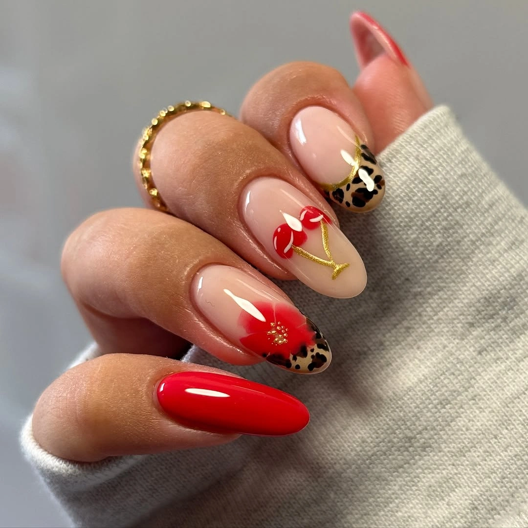 Long almond red nails with floral nude accents and spotted tips
