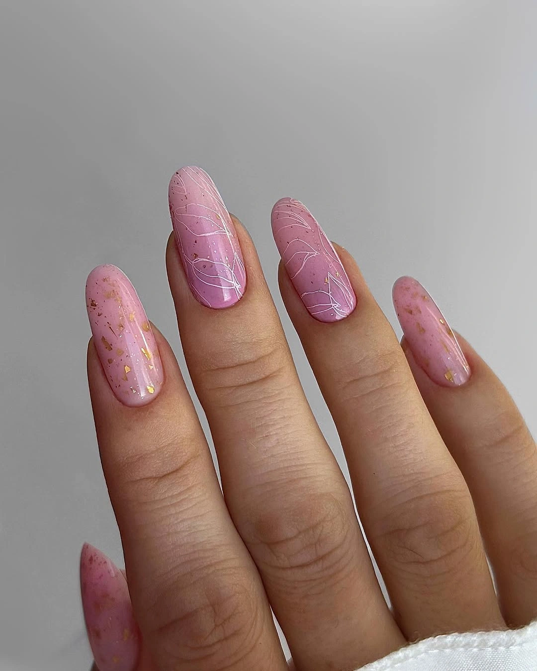 Long soft pink almond nails with airy white linework and small gold flecks