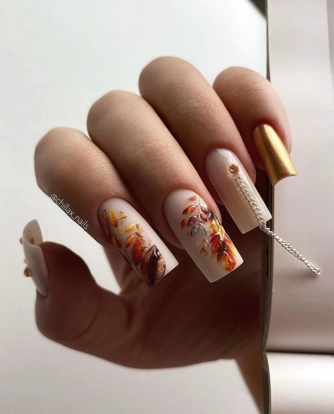 Long nude square nails with layered brown and rust leaf illustrations