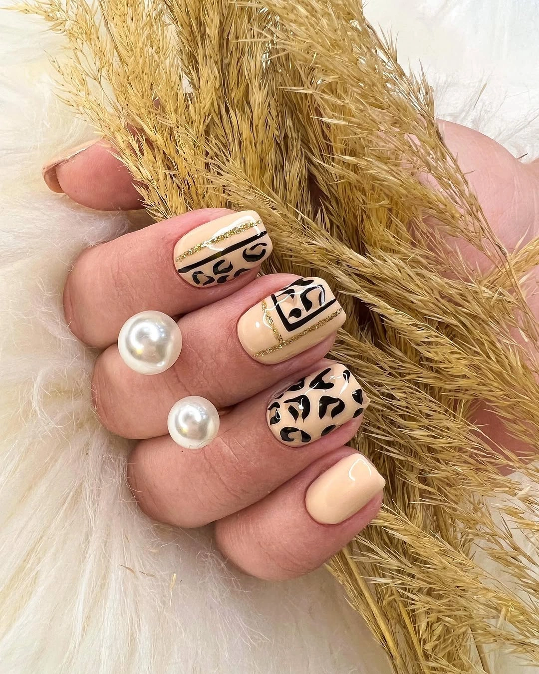 Cream and beige almond nails with irregular black animal-inspired print
