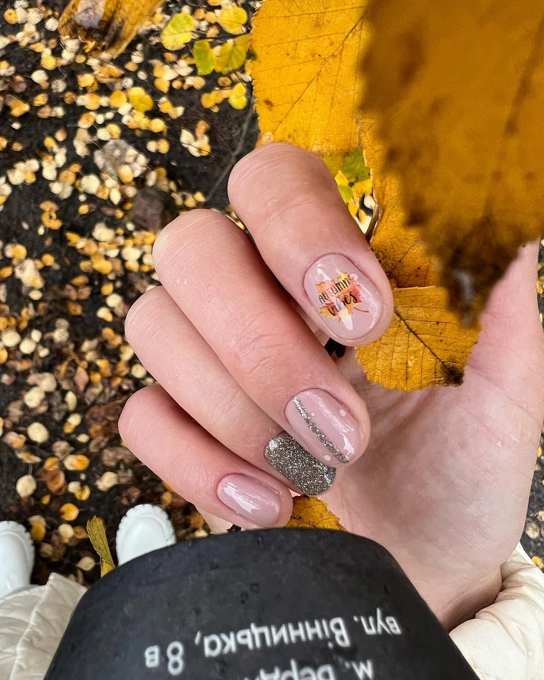 Short pale pink nails with tiny warm accents and one reflective nail
