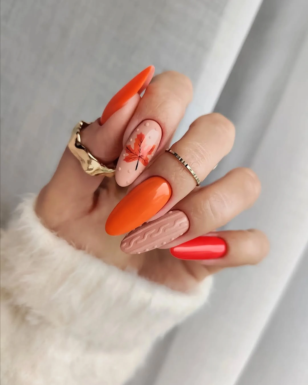 Long almond orange and red fall nails with one pale pink accent