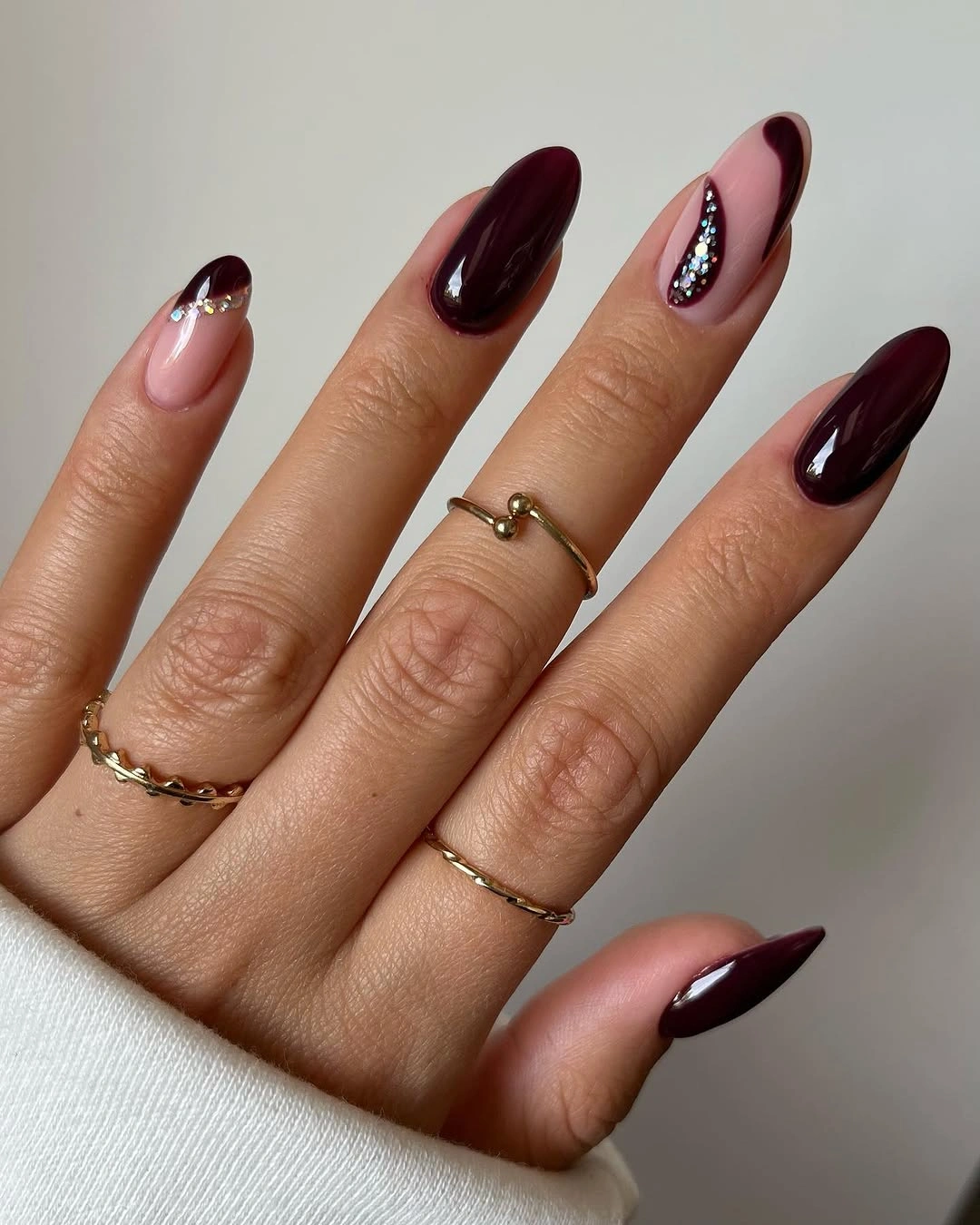 Long almond burgundy nails with one pale accent and curved bright details
