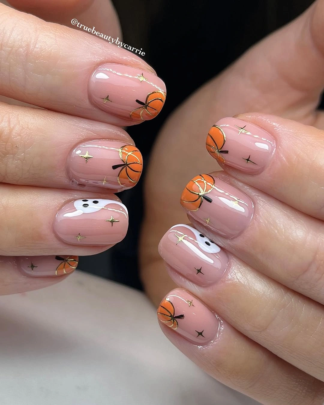 Short rounded blush fall nails with orange motifs dark marks and gold flecks