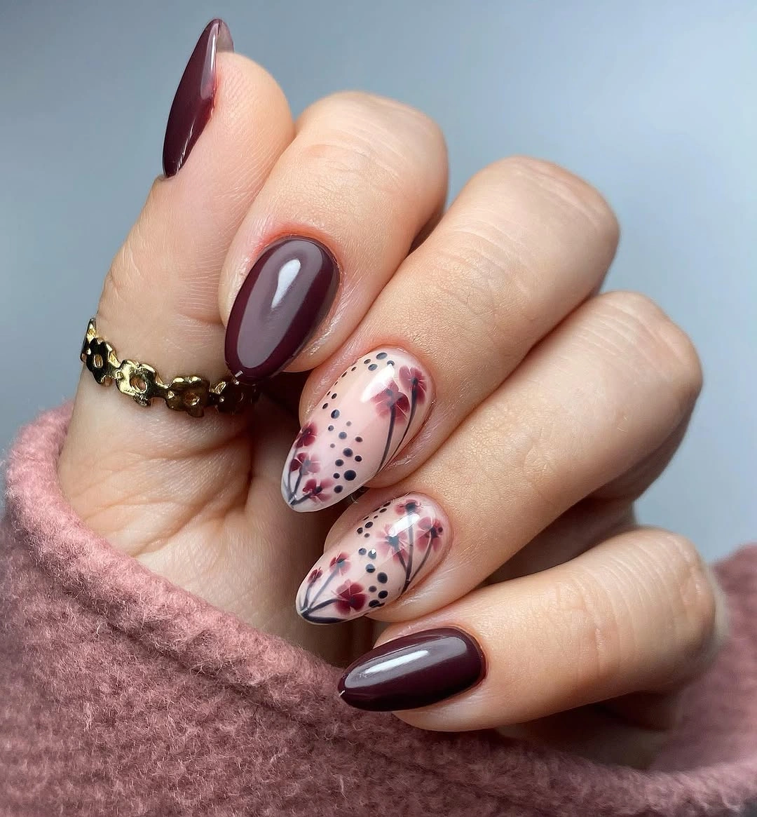 Medium almond burgundy nails with pale floral accent panels and dark dots