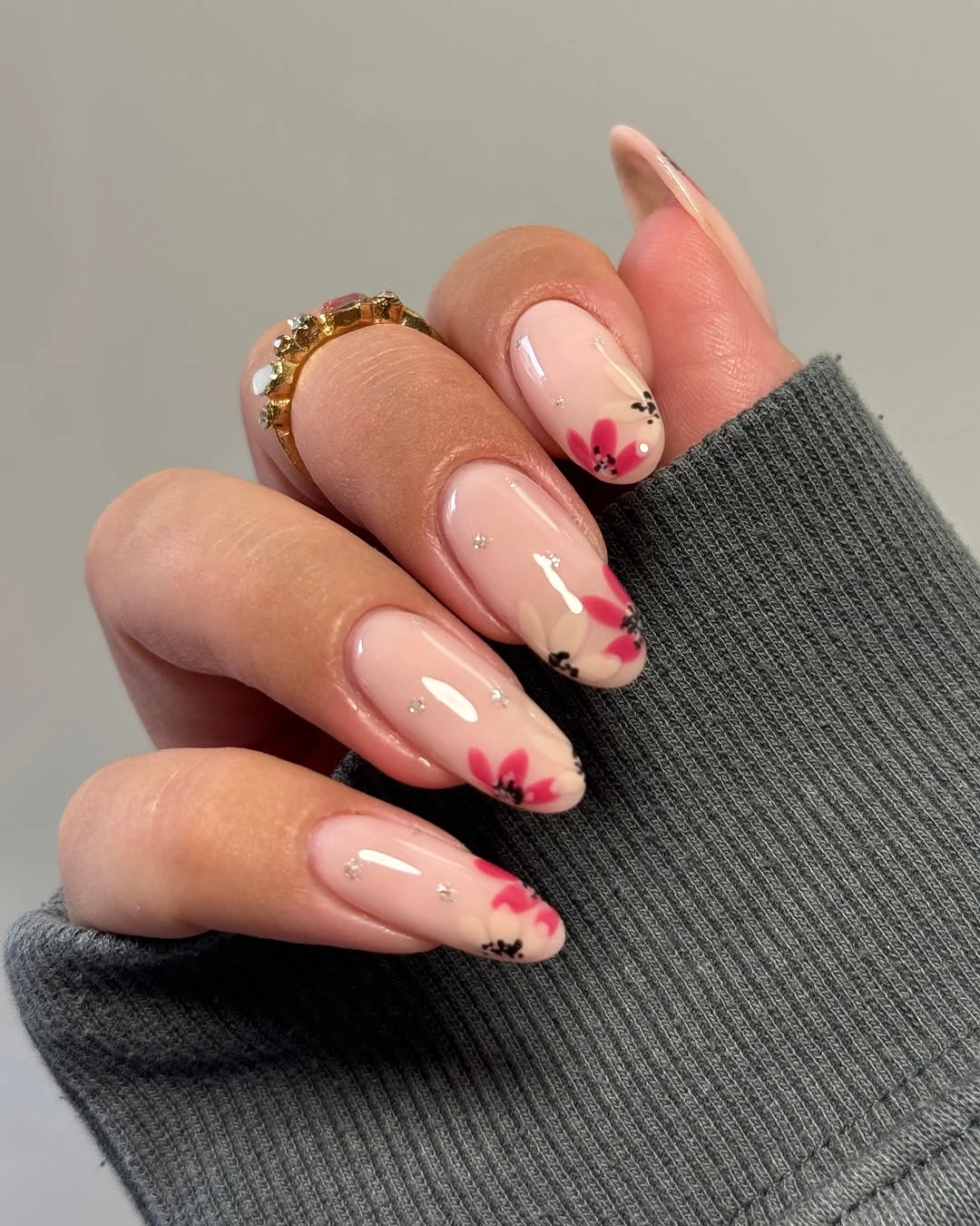 Medium almond nude nails with small red orange floral accents
