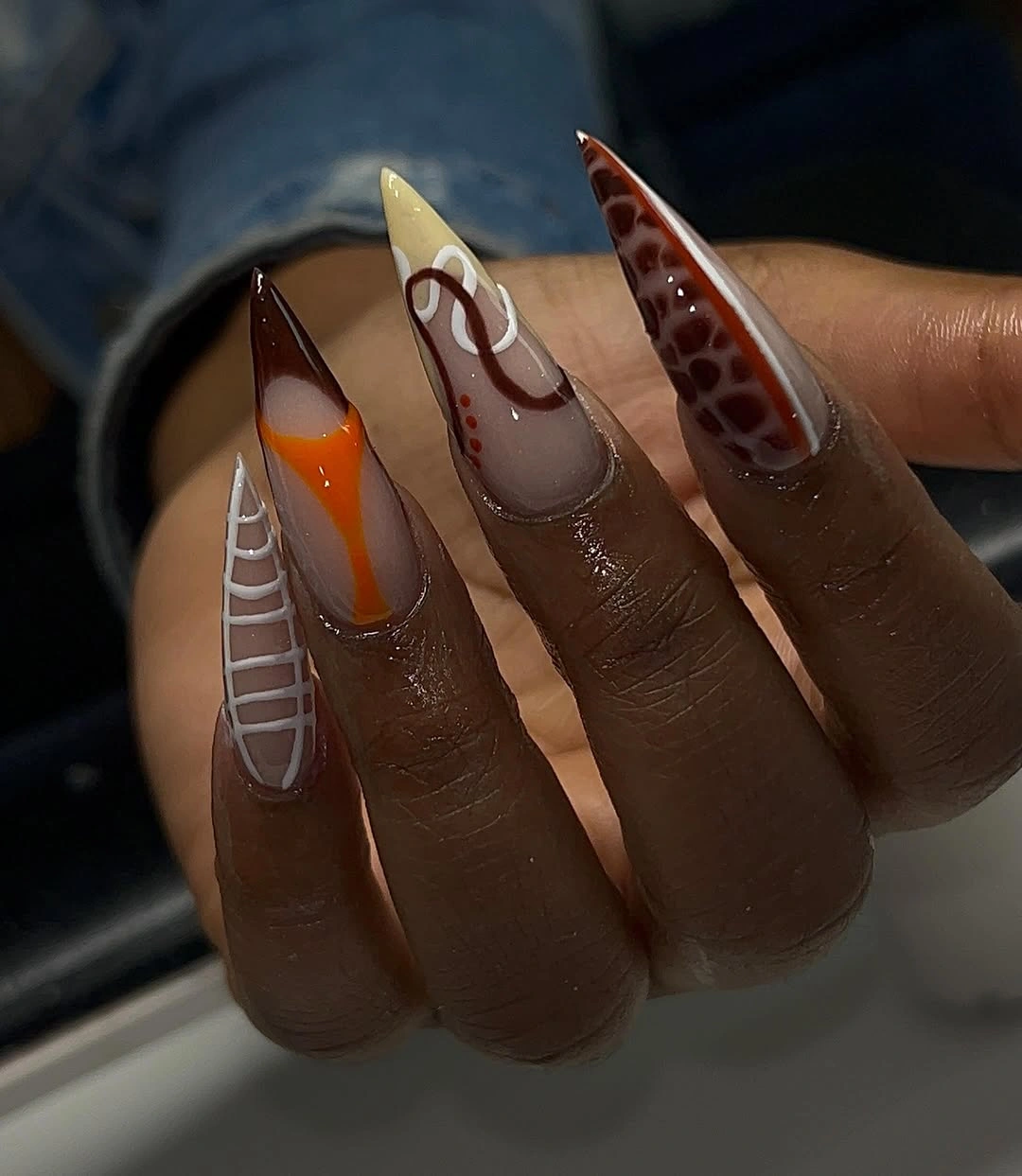 Long stiletto brown orange nails with spots and pale lines