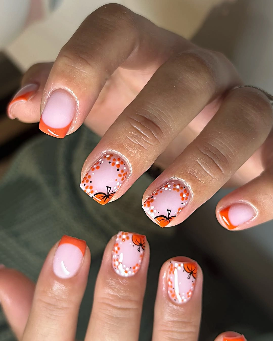 Short pink nails with orange French tips and pumpkin borders