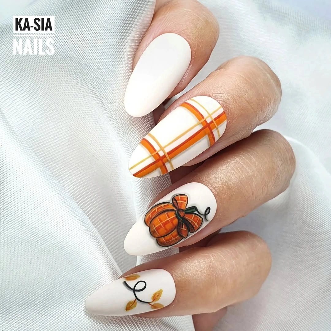 White almond nails with orange plaid, pumpkin, and leaf accents