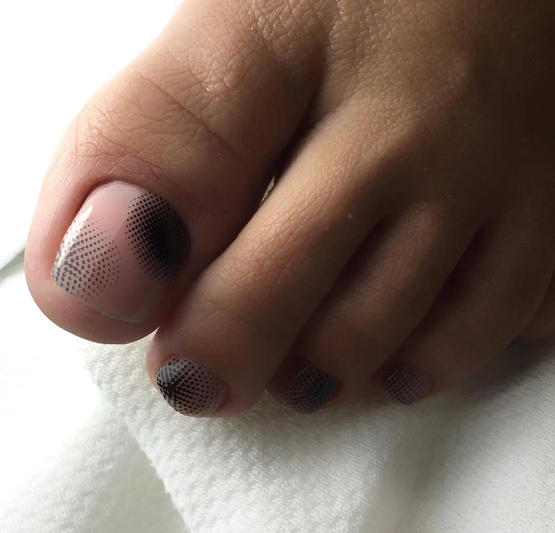 Nude pedicure with smoky black dotted design