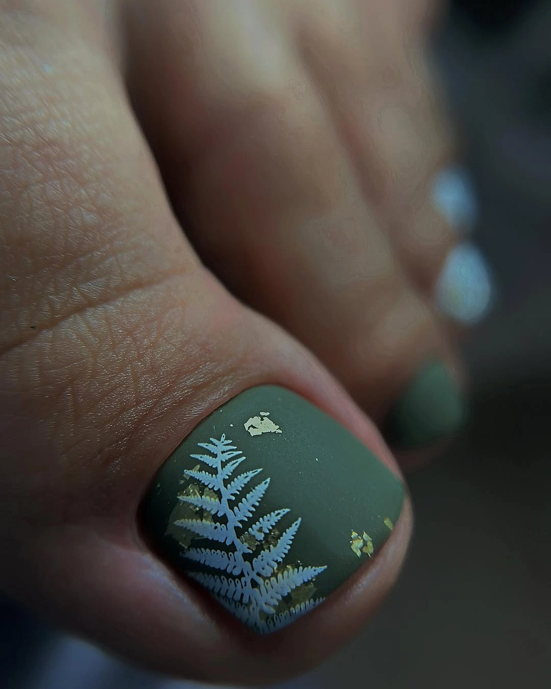 Muted green pedicure with white fern art