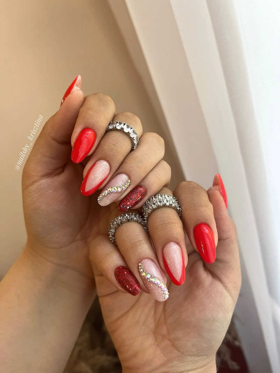 Red glitter almond nails with blush rhinestone accents