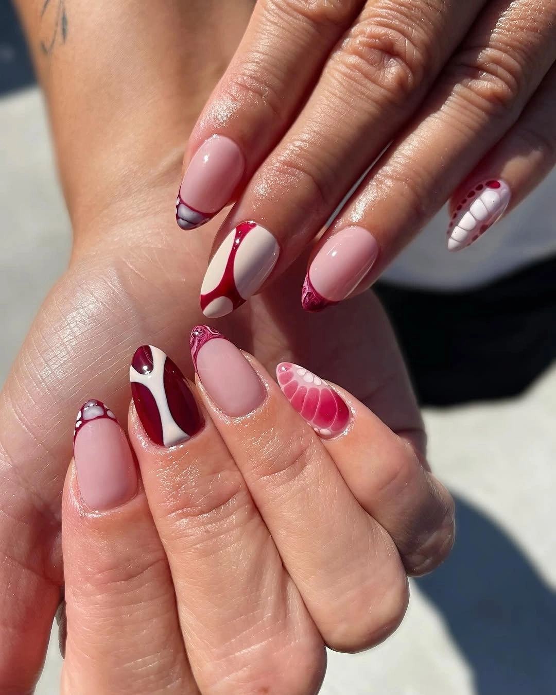 Blush almond nails with burgundy red and dark green graphics