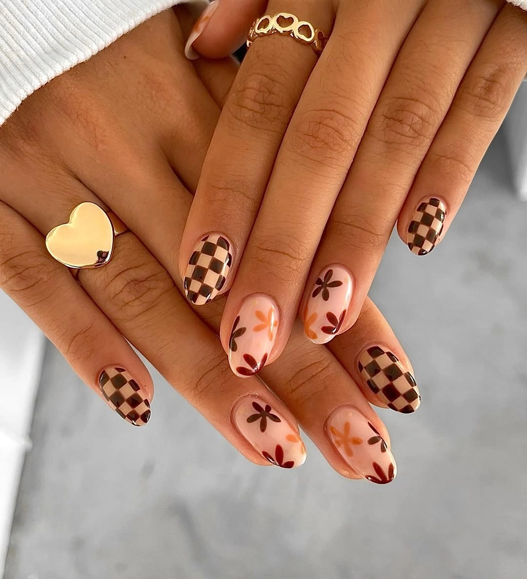 Sheer almond nails with brown checkerboard tips and tiny florals