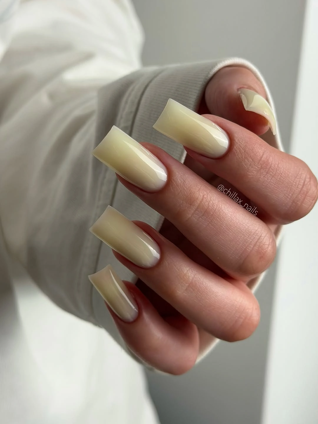 Long square nails in a uniform creamy pale yellow glossy shade