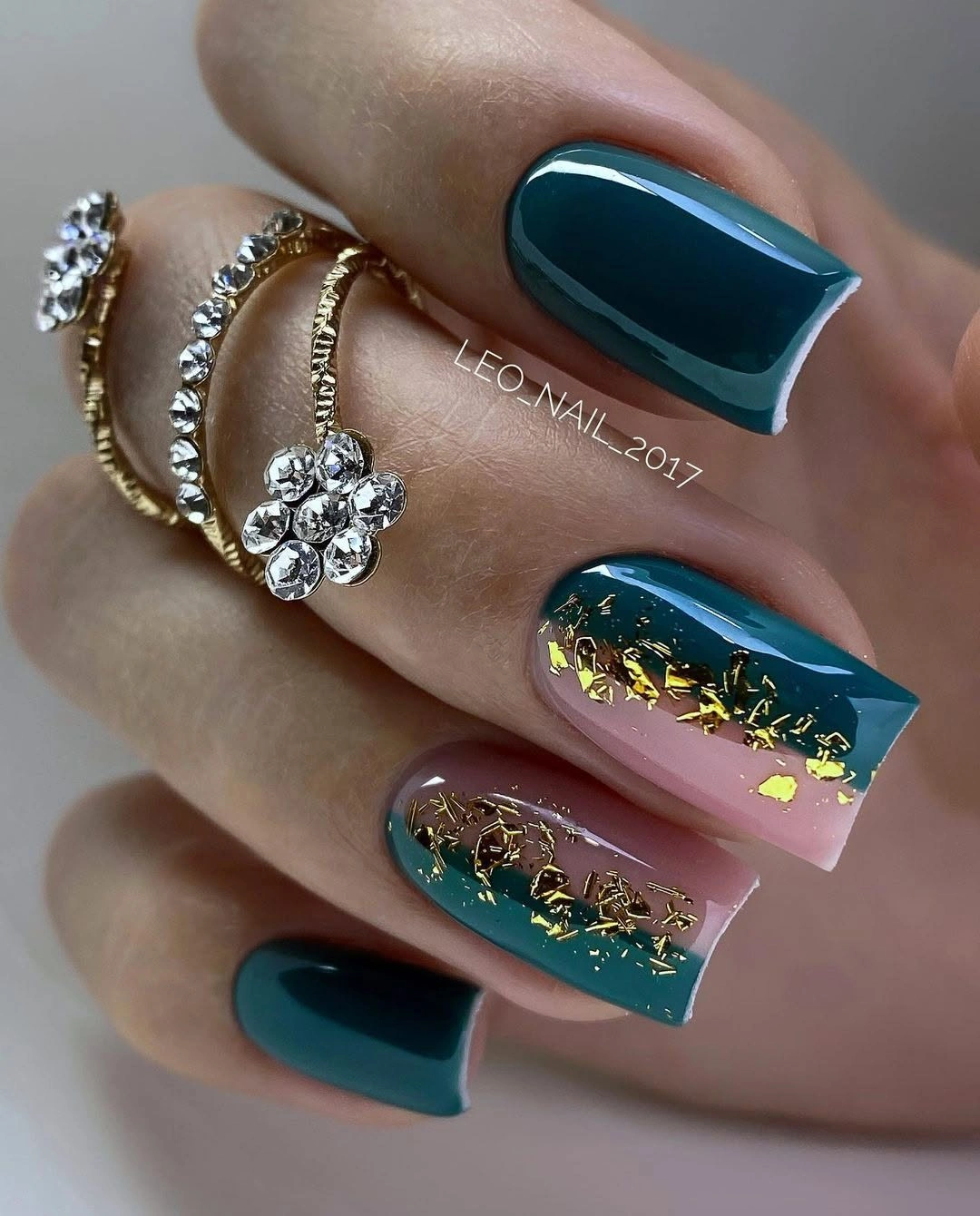 Long square nails in deep teal dusty pink and pale tones with small gold-toned flecks