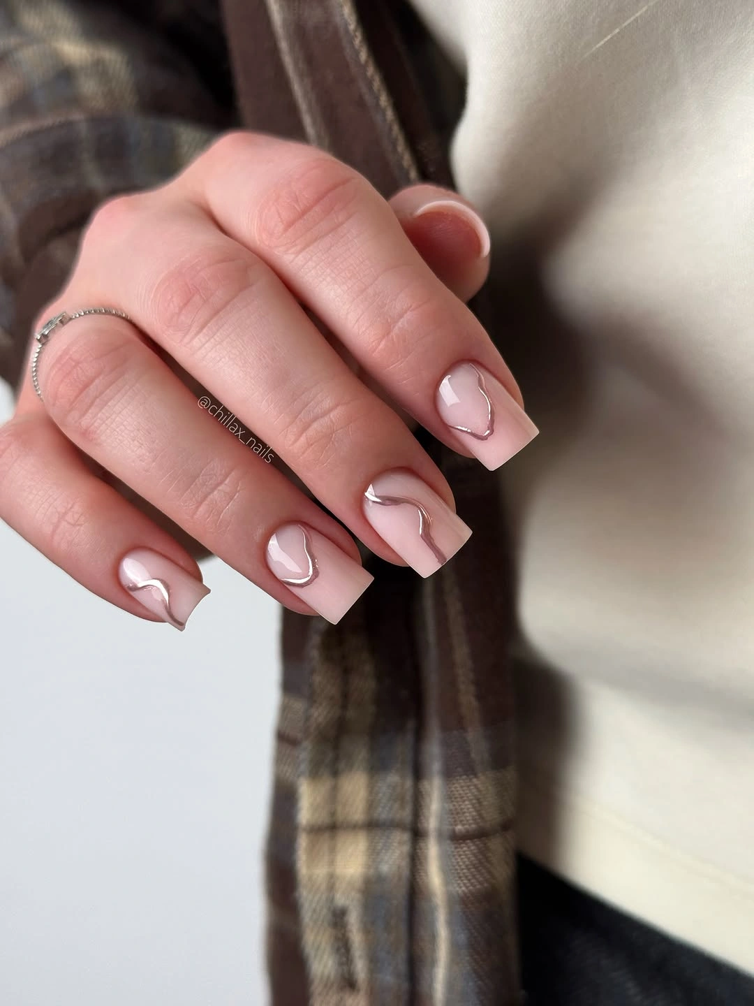 Short pale pink square nails with slim dark negative-space curves near the tips