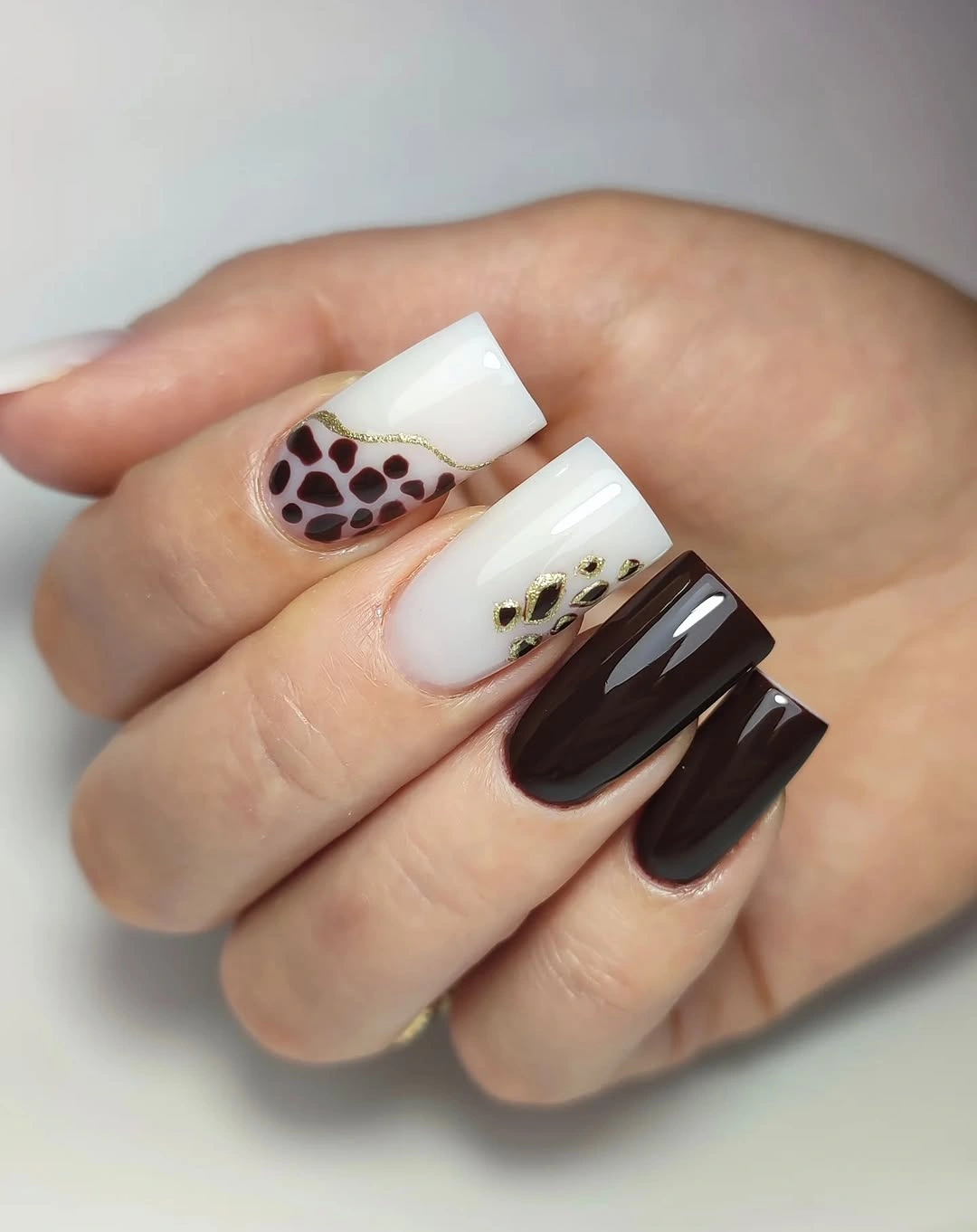 Long square nails in creamy white and espresso brown with irregular spotted accents and small flecks