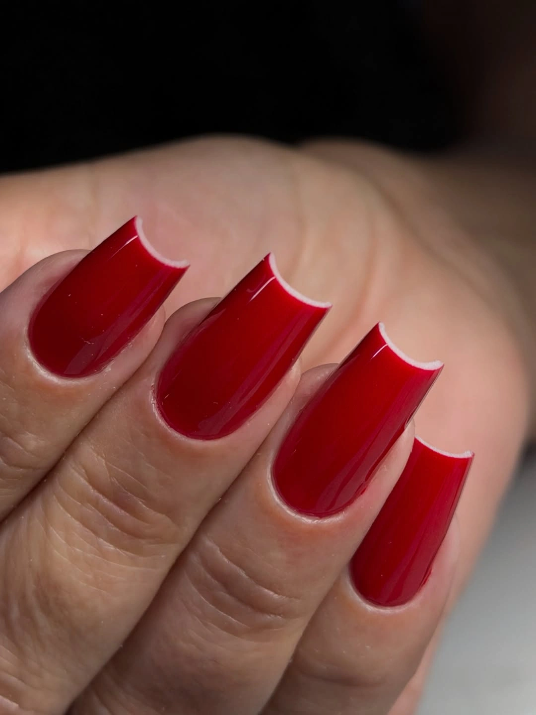 Long tapered square nails in glossy red with a narrow pale edge outline