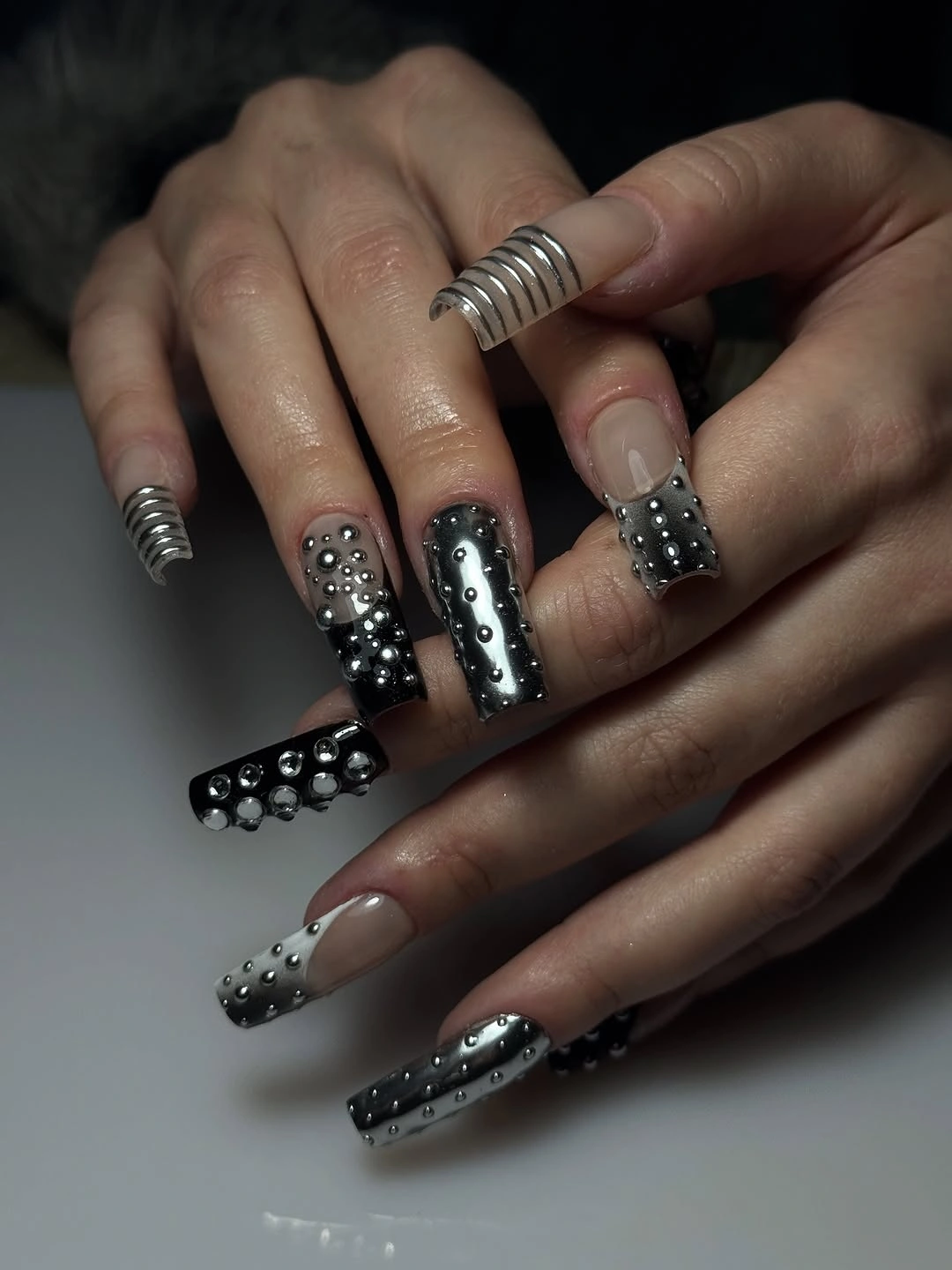 Long square nails in black nude and white with dense dot patterns and small accents