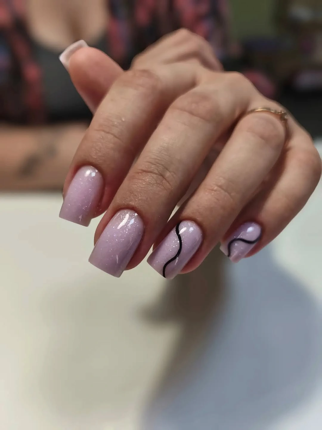 Medium mauve square nails with thin dark wavy lines and pale rounded details