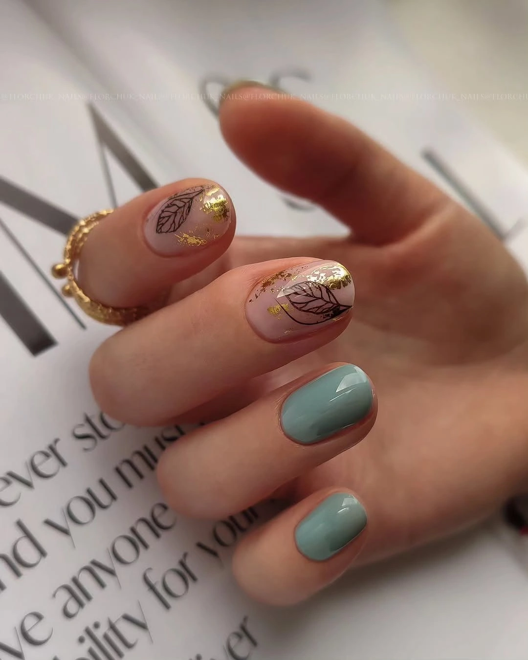 Short rounded teal and blush nails with tiny black motifs