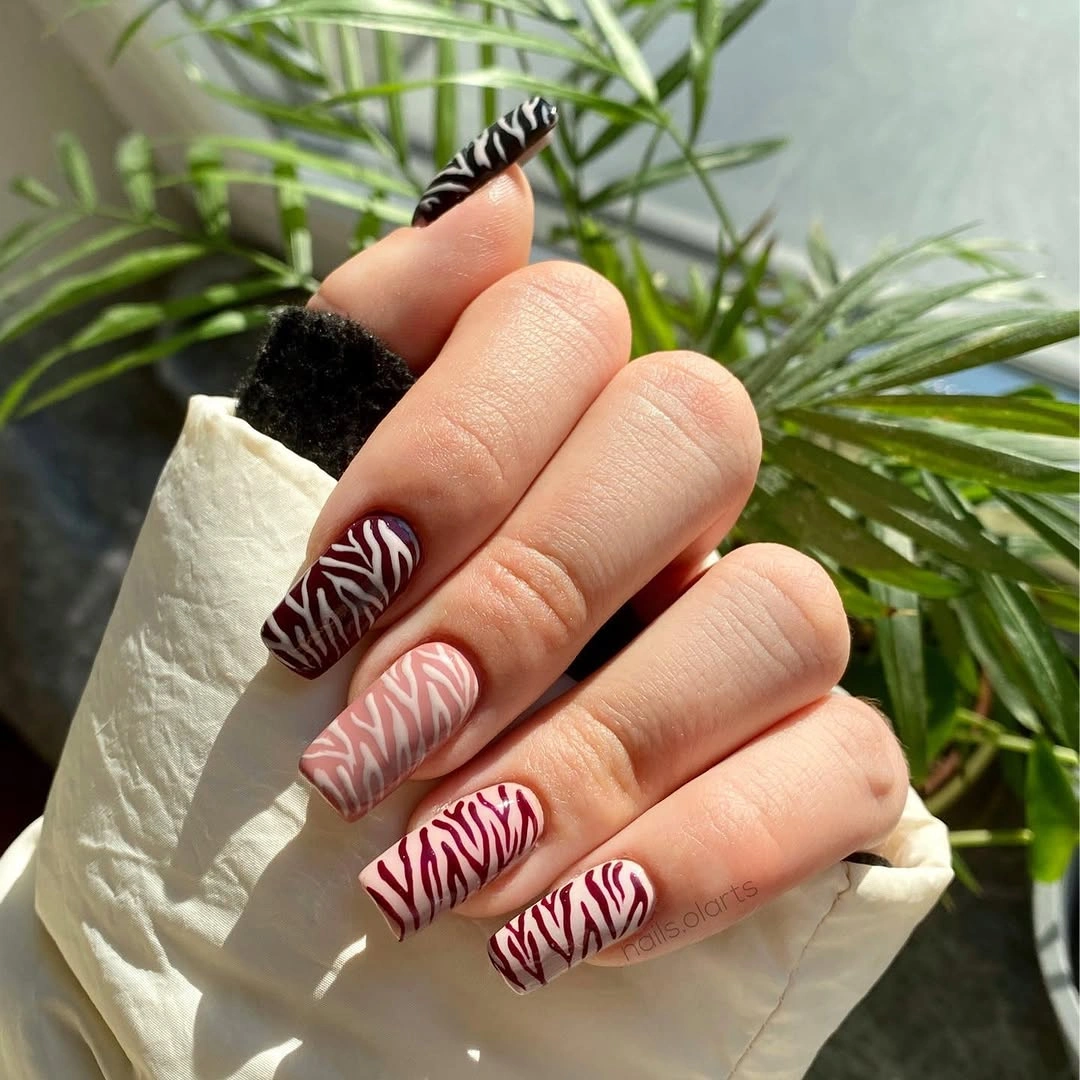 Long pale pink nails with bold black and white wavy stripes