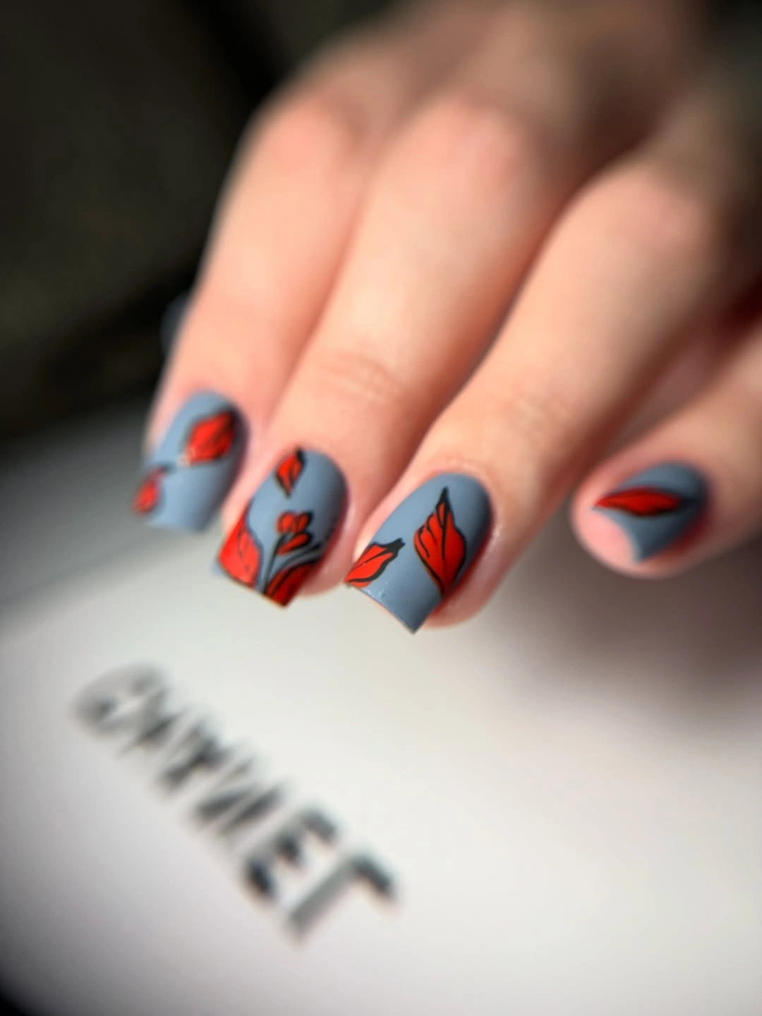 Short pale blue nails with red black and orange tip graphics