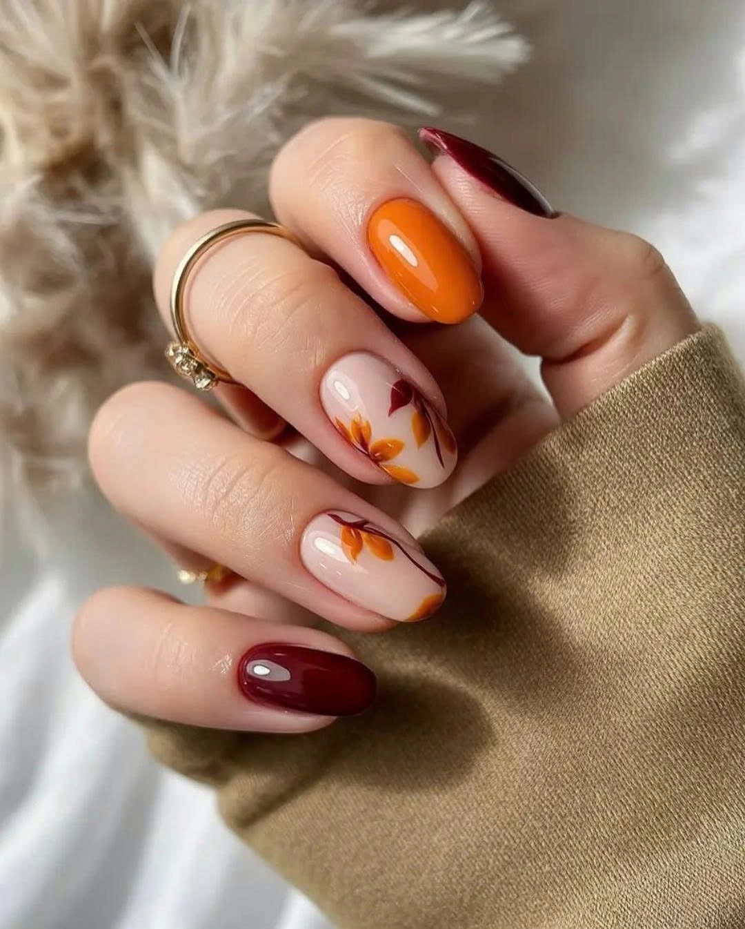 Short oval burgundy and burnt orange nails with leaves
