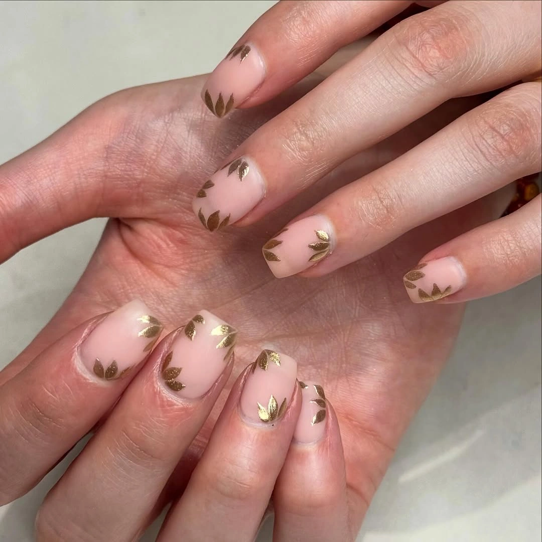 Squared nude nails with sparse metallic gold leaf clusters