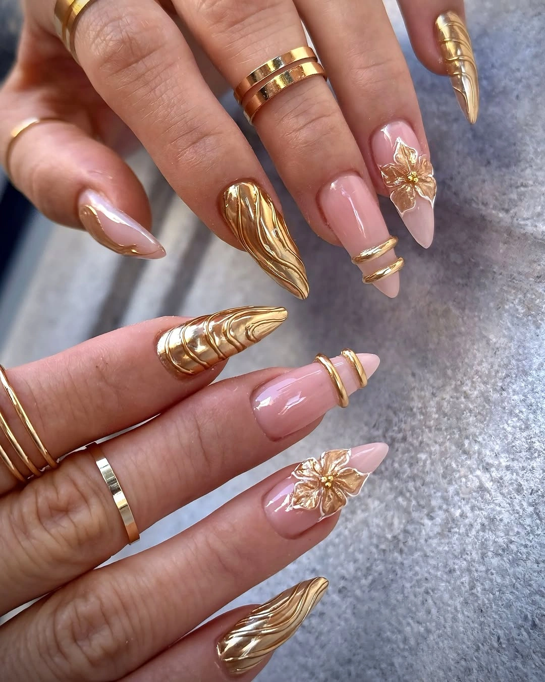Blush pointed nails with sculptural gold flowers and bands
