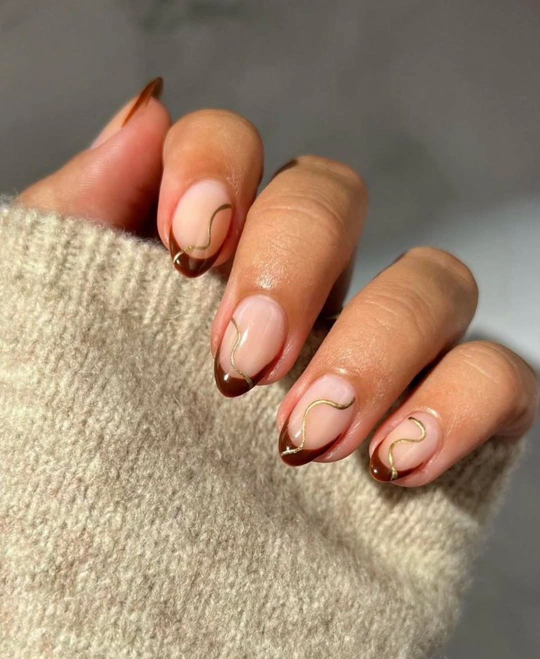 Short sheer nails with chocolate French tips and gold curves
