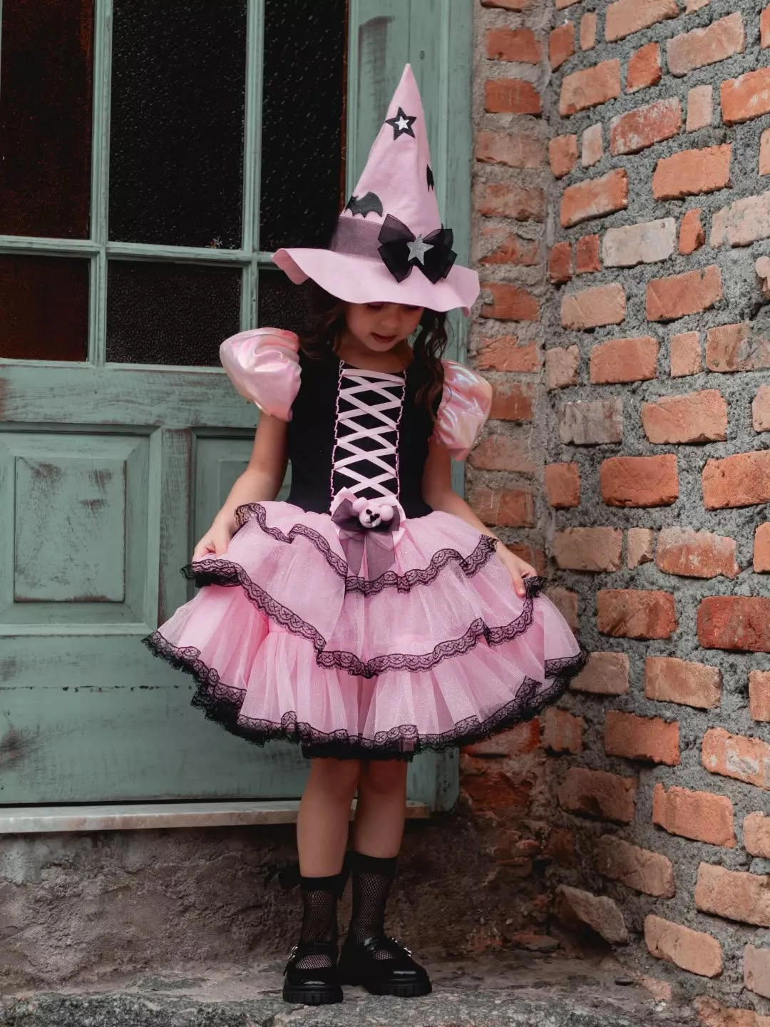 Pink witch child costume with cone hat, lace-up bodice, layered skirt, and boots