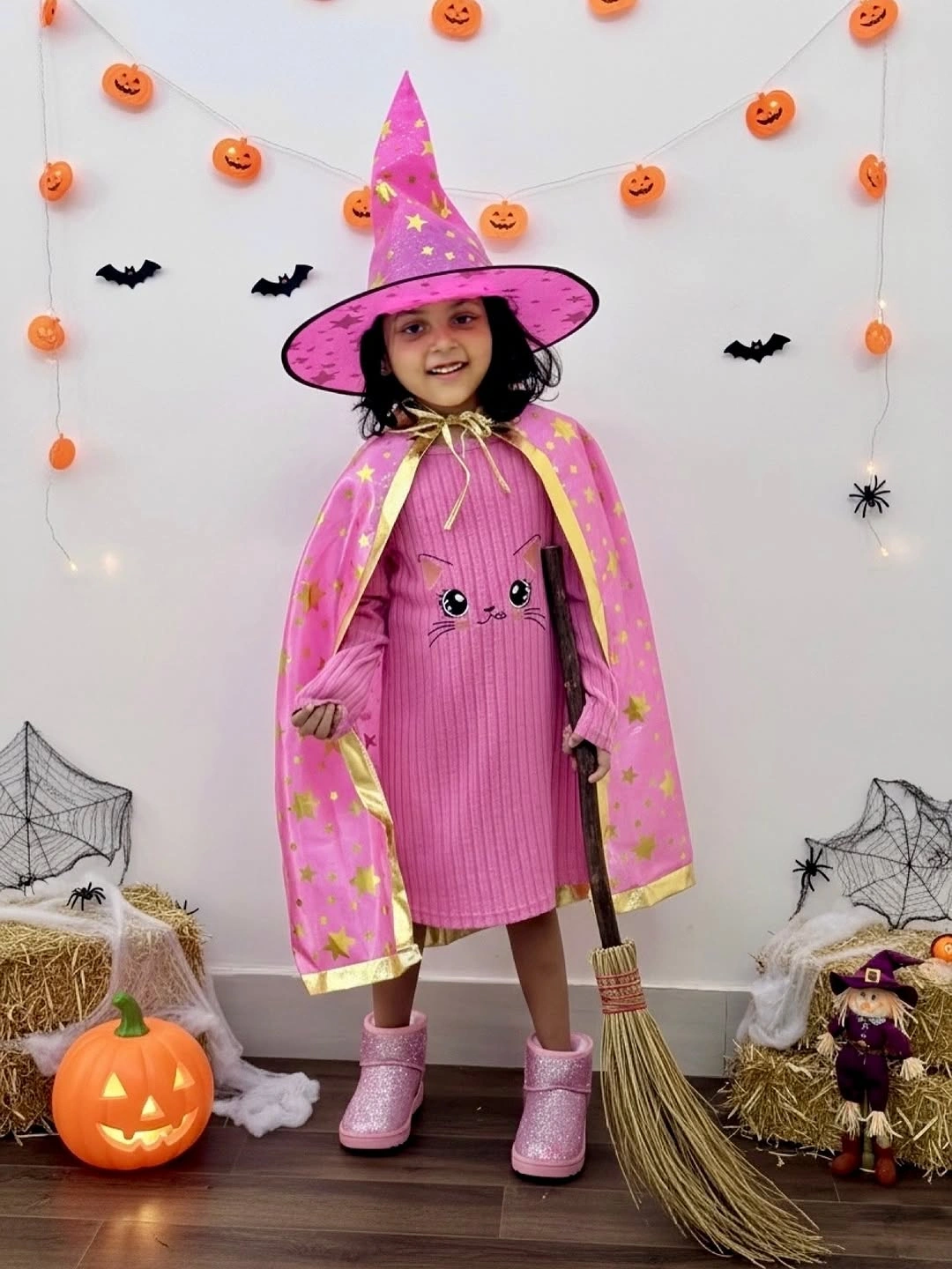 Pink cape witch child costume with cone hat, striped dress, pink boots, and broom