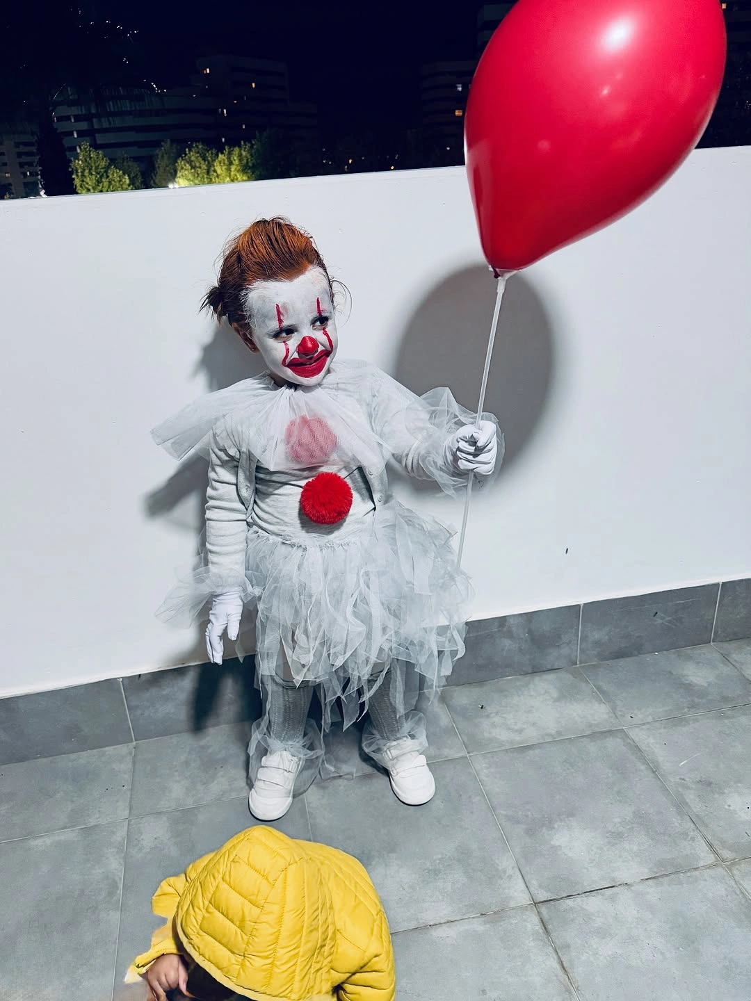 Child dressed as Pennywise from It holding a red balloon