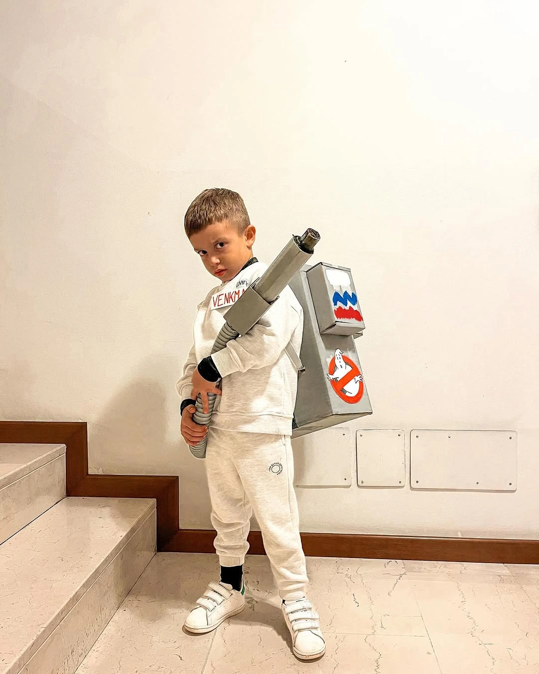 Young astronaut costume in white space jumpsuit with patches and rocket prop