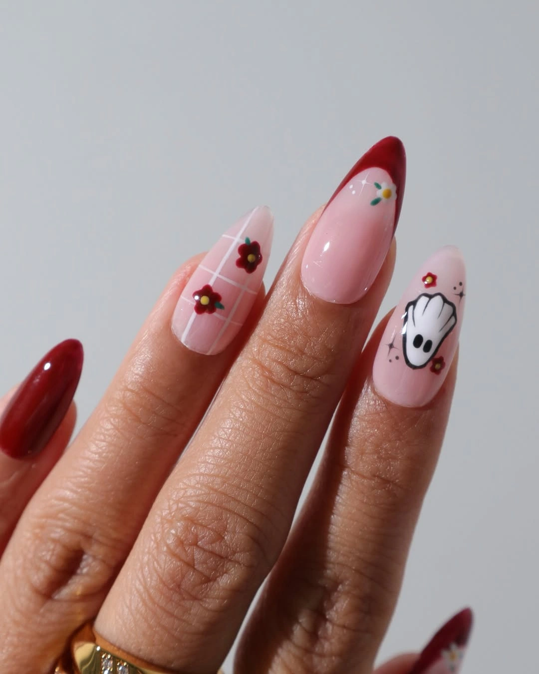 Pink almond nails with red tips, flowers, and white ghost art