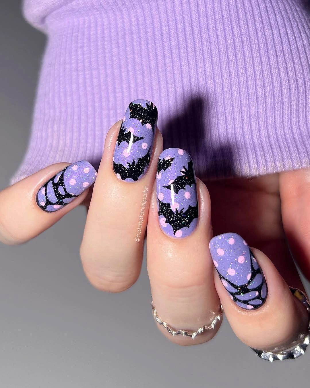 Lavender rounded nails with black bats, moon, and dot details