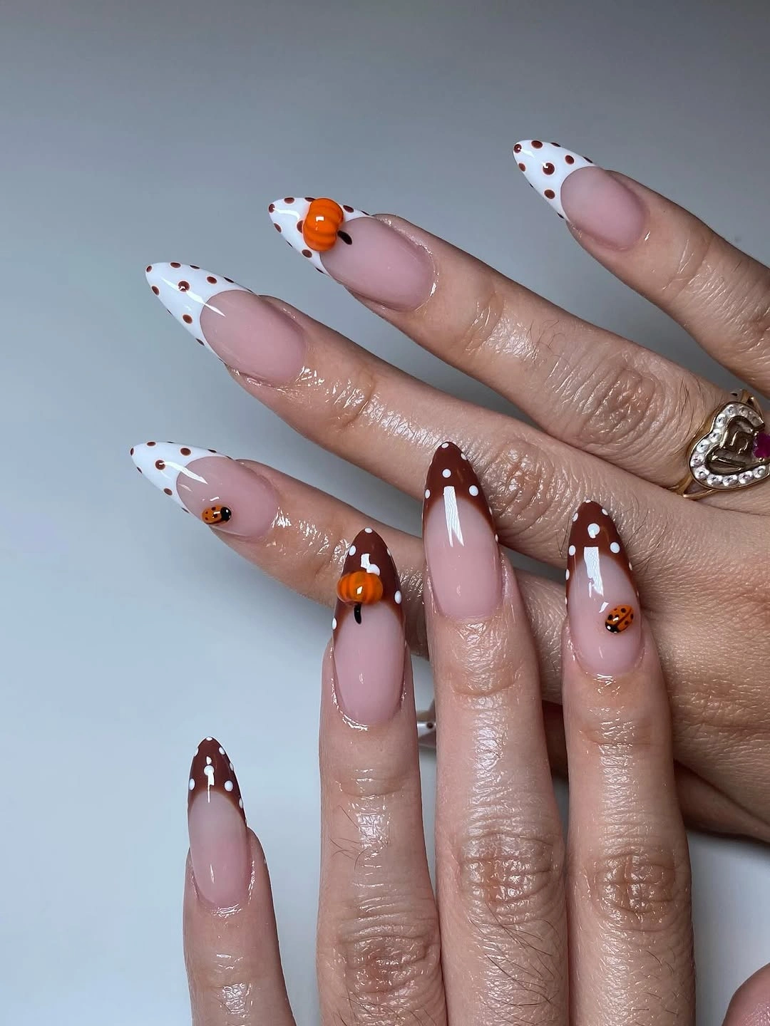 Long almond nails with dotted tips and tiny orange pumpkins