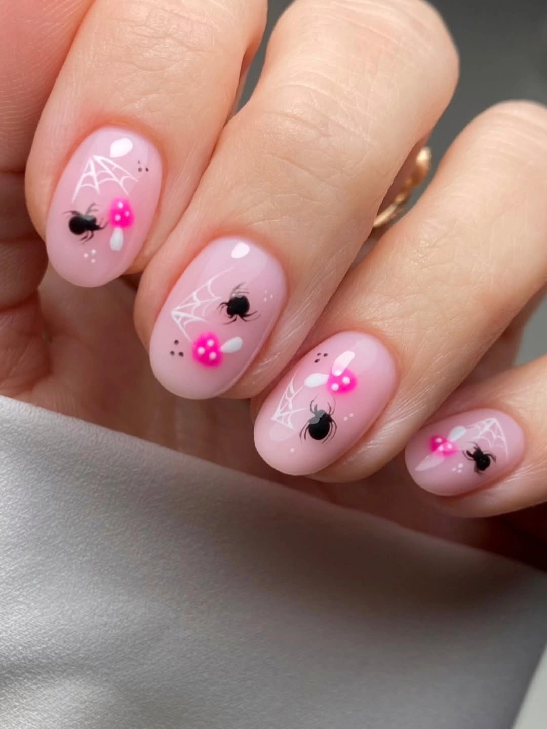 Short pink nails with white webs and tiny black spiders