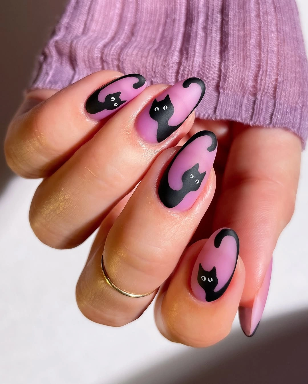 Pink almond nails with repeated black cat silhouettes